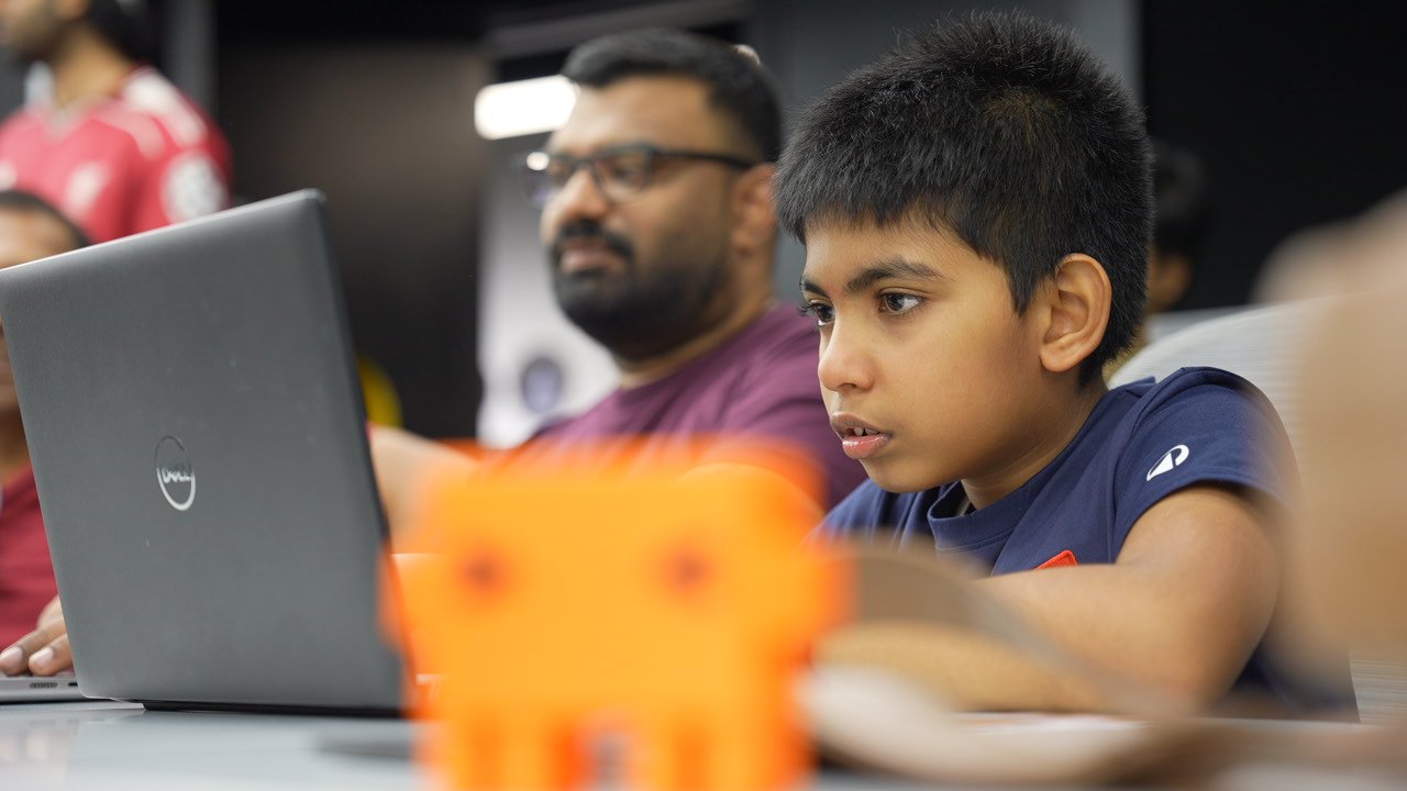Lakshveer at the laptop, robot in the foreground